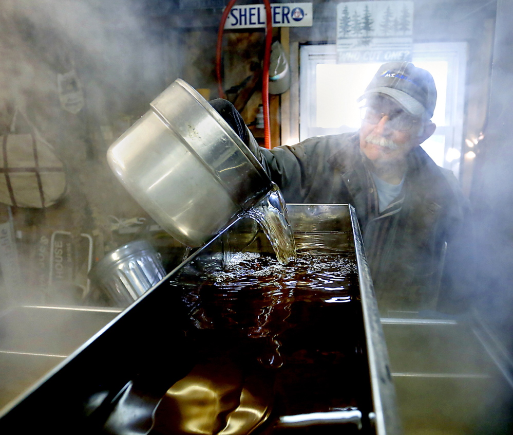 At Grandpa Joe’s Sugar House in Baldwin, Steven McKenney pours sap into a pan that rests on the wood-fired evaporator.