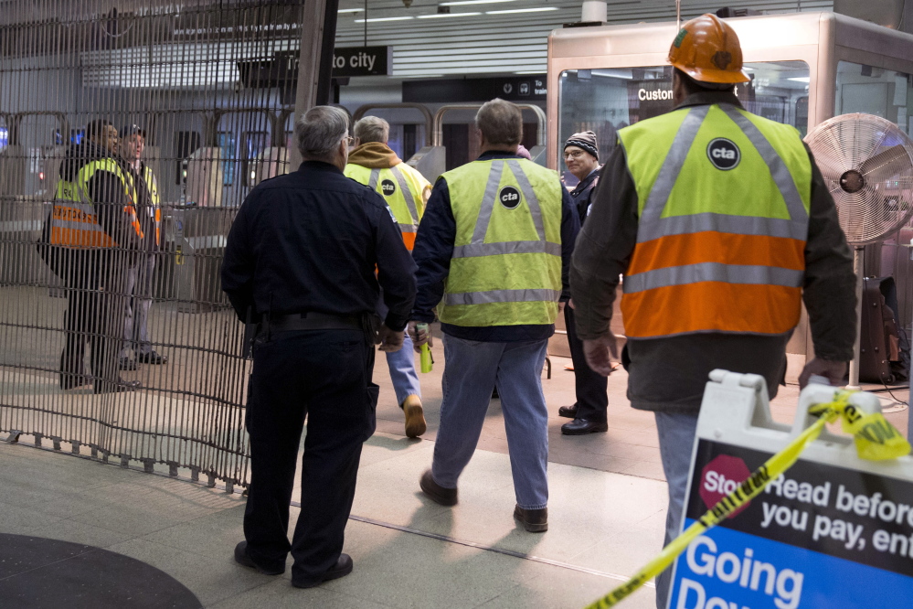 Chicago Transit Authority employees work the scene where a Chicago Transit Authority derailed at the O’Hare Airport station early Monday. More than 30 people were injured after the eight-car train plowed across a platform and scaled an escalator at the underground station.