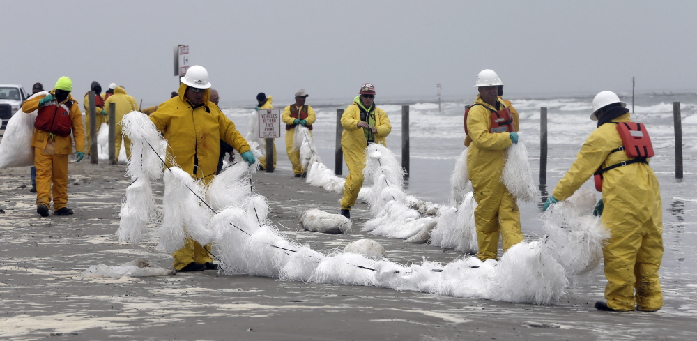 Crew members spread a viscous snare along East Beach to trap oil Monday in Galveston, Texas. Thousands of gallons of tar-like oil spilled into the major U.S. shipping channel after a barge ran into a ship Saturday.