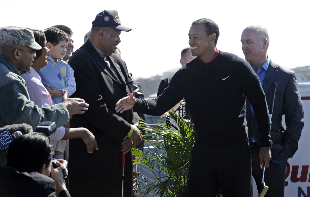Tiger Woods, second from right, shakes hands following a putting challenge at the Newseum in Washington, Monday.