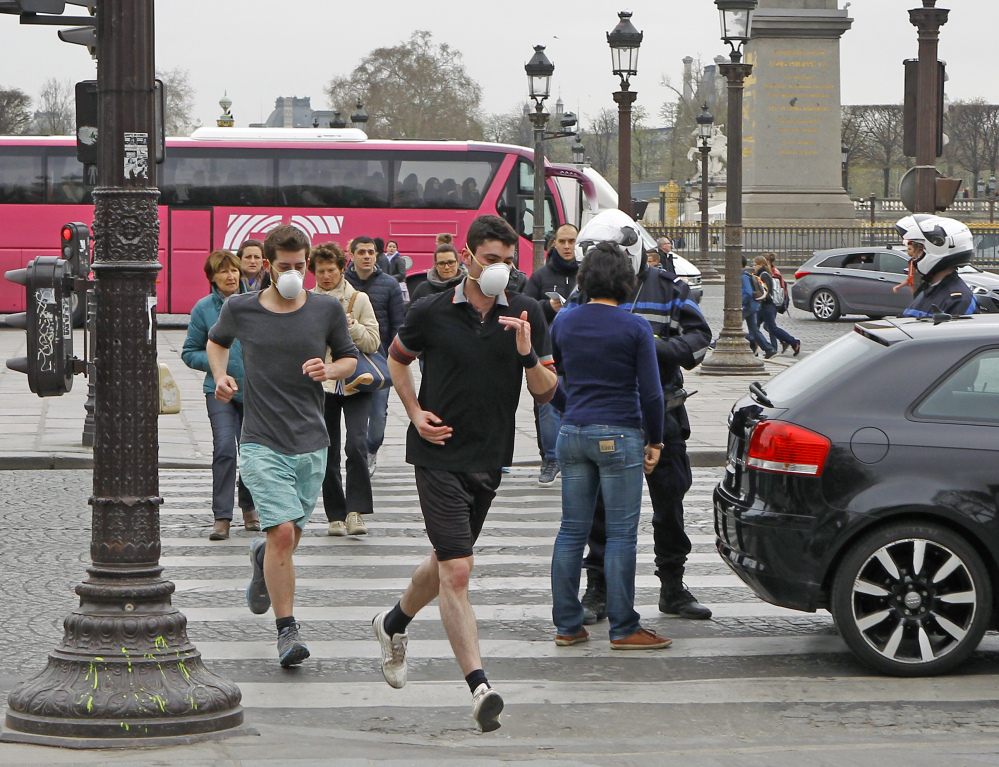 Two joggers wearing face masks run through the Place de la Concorde in Paris on Friday. Noting an increasing use of face masks in heavily polluted cities such as Beijing and Tokyo, scientists say the masks’ effectiveness is unclear.