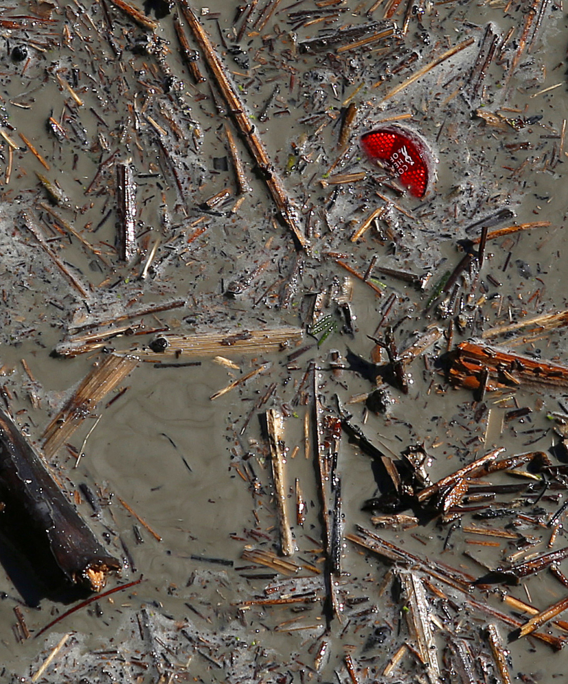 A reflector is seen in the debris slowly flowing down the Stillaguamish River after the slide blocking the river started letting water through on Sunday.