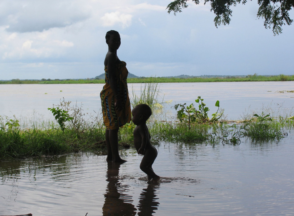 A woman and child wade in flood waters in Mutarara, Mozambique. Thousands of people who lost their homes in floods last year are at risk again as the rising Zambezi river waters threaten their resettlement camps.