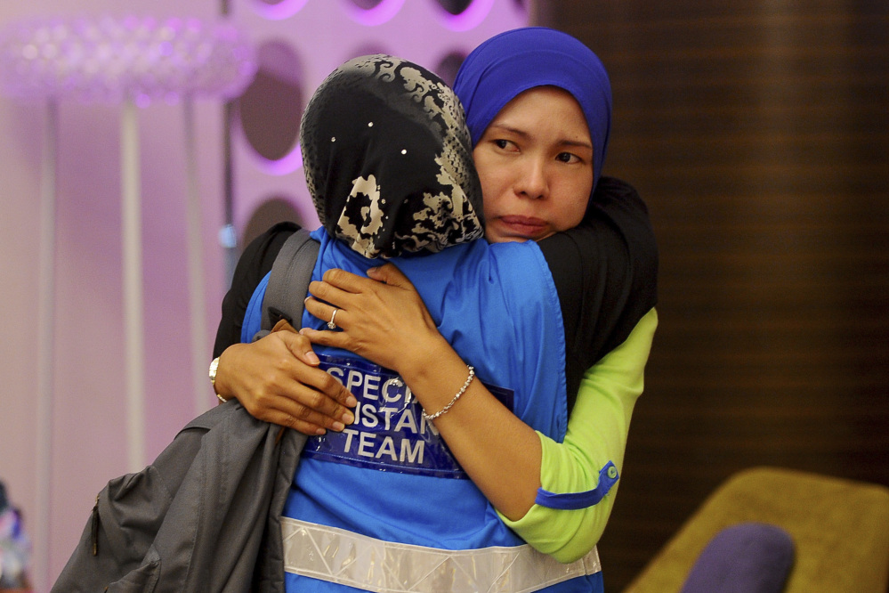 A family member, right, of passengers aboard a missing Malaysia Airlines plane is embraced by a member of Special Assistance Team at a hotel in Putrajaya, Malaysia, Tuesday, March 25, 2014. Malaysia said Tuesday that it has narrowed the search for a downed jetliner to an area the size of Texas and Oklahoma in the southern Indian Ocean, while Australia said improved weather would allow the hunt for possible debris from the plane to resume.