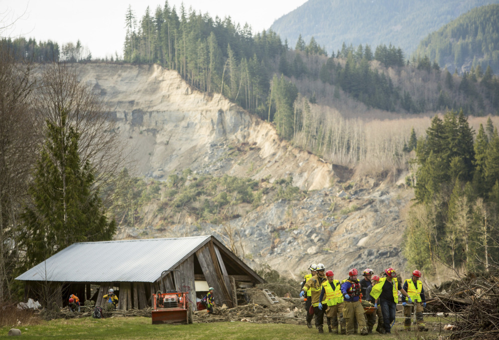 Rescue workers remove one of a number of bodies from the wreckage of homes destroyed by a mudslide near Oso, Wash., Monday.