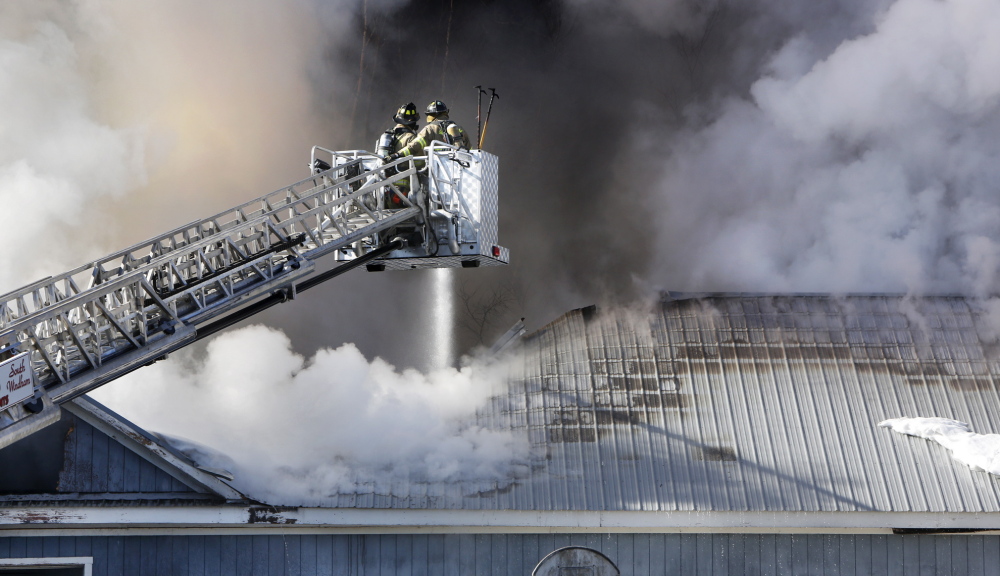 Windham firefighters direct water through the roof of Town & Country Cabinets in Gorham on Tuesday. The fire may have started around an exhaust fan on the second floor, where smoke was initially spotted, said Gorham Fire Chief Robert Lefebvre.