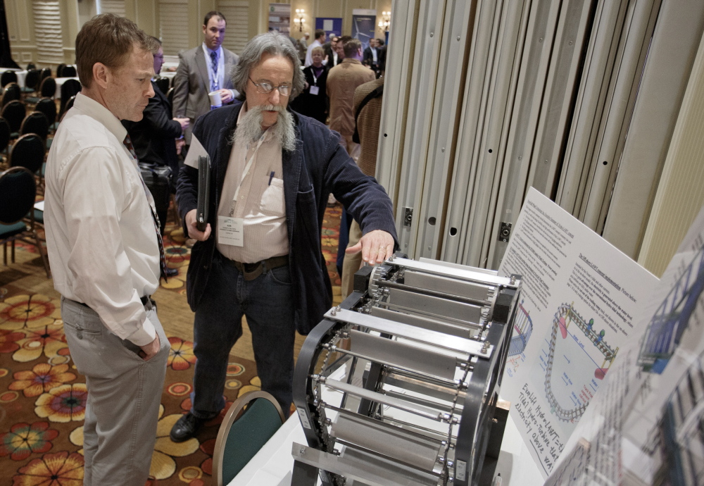 Warren Schmelzer, left, of EverLift Inc. and Ken Baldwin of the University of New Hampshire discuss one of EverLift’s new turbine designs Tuesday at a wind energy summit.