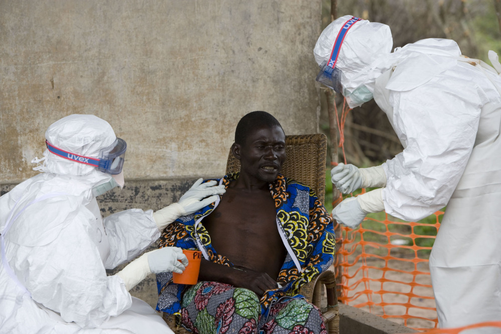 A Congolese patient, center, who was confirmed to have Ebola hemorrhagic fever is comforted by Doctors without Borders personnel in Kampungu, Kasai Occidental province, Congo, in September 2013. An outbreak of the deadly Ebola virus is believed to have killed at least 59 people in Guinea and may already have spread to neighboring Liberia, health officials said Monday.