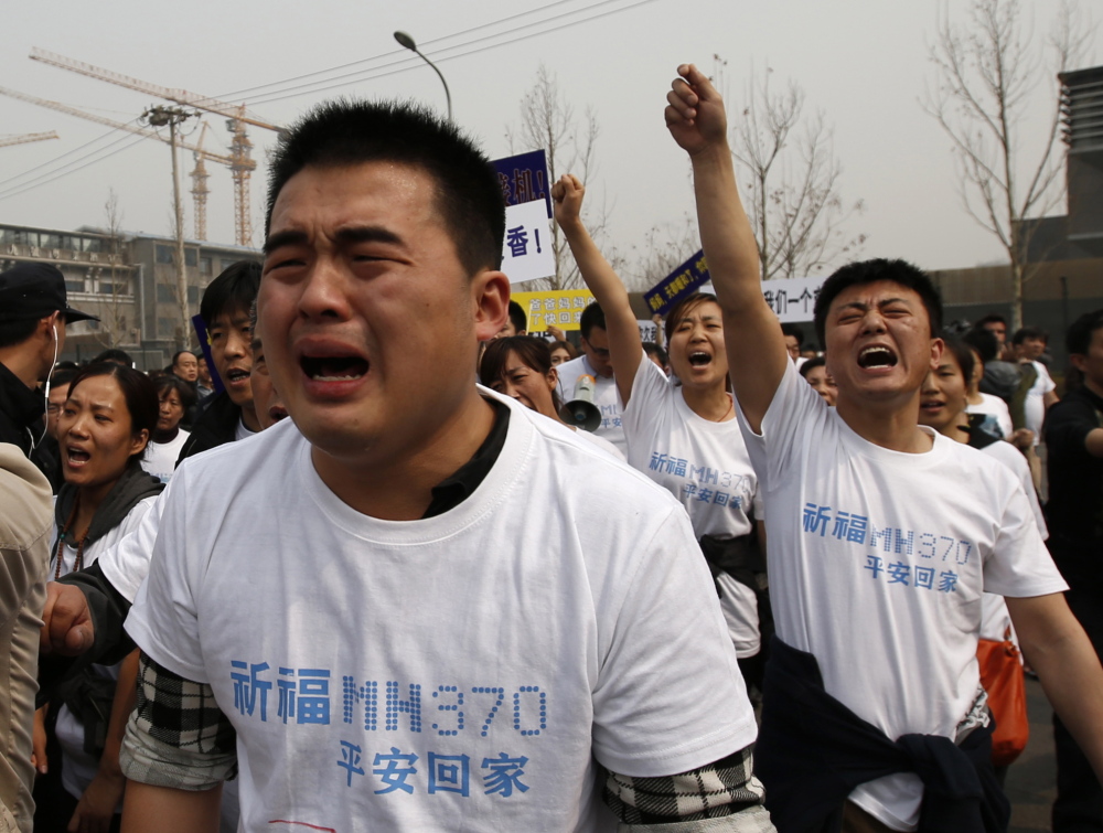 Family members of passengers on Malaysia Airlines Flight 370 cry as they shout slogans during a protest in front of the Malaysian embassy in Beijing on Tuesday. Relatives of passengers accused the Southeast Asian country of “delays and deception.”