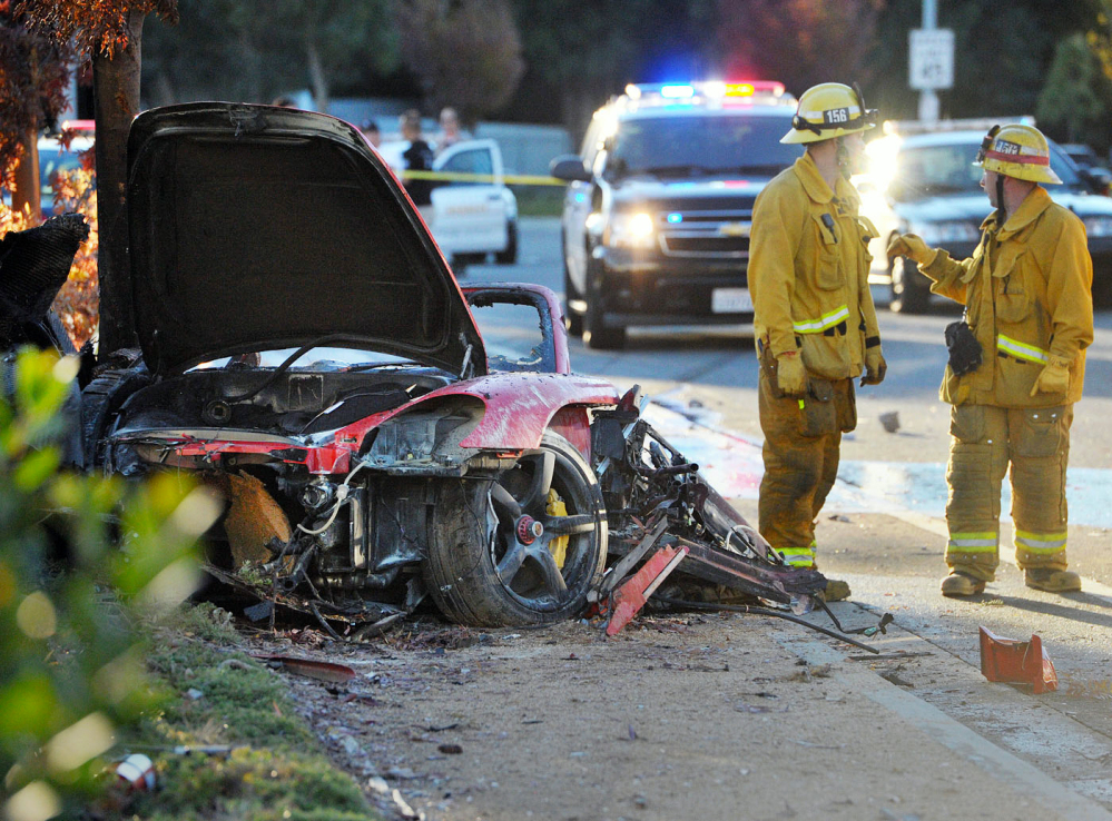 Firefighters work next to the wreckage of a Porsche that crashed into a light pole killing actor Paul Walker and Roger Rodas in Valencia, Calif. Crash investigators have determined that the Porsche was traveling approximately 90 mph at the time, according to someone who has seen the report.