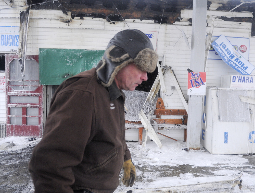 Webb’s Store owner Dan Kilmer walks past the burned business Wednesday morning after an early morning fire. Kilmer said his security firm called him at 3 am to report an alarm and when he arrived minutes later the building was engulfed in smoke.