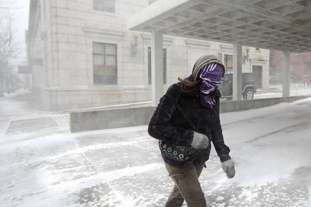 A woman fights through wind-driven snow as she crosses a street during a spring snowstorm in downtown New Bedford, Mass., on Wednesday.