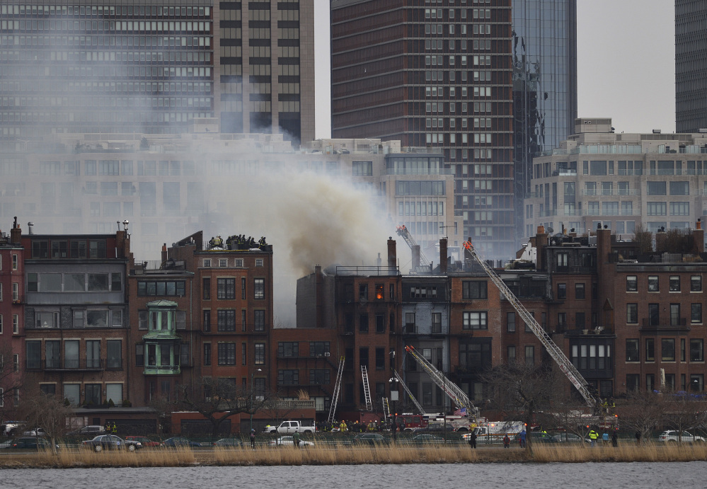Smoke pours from the burning Boston brownstone, seen from Cambridge, Mass., as firefighters respond.