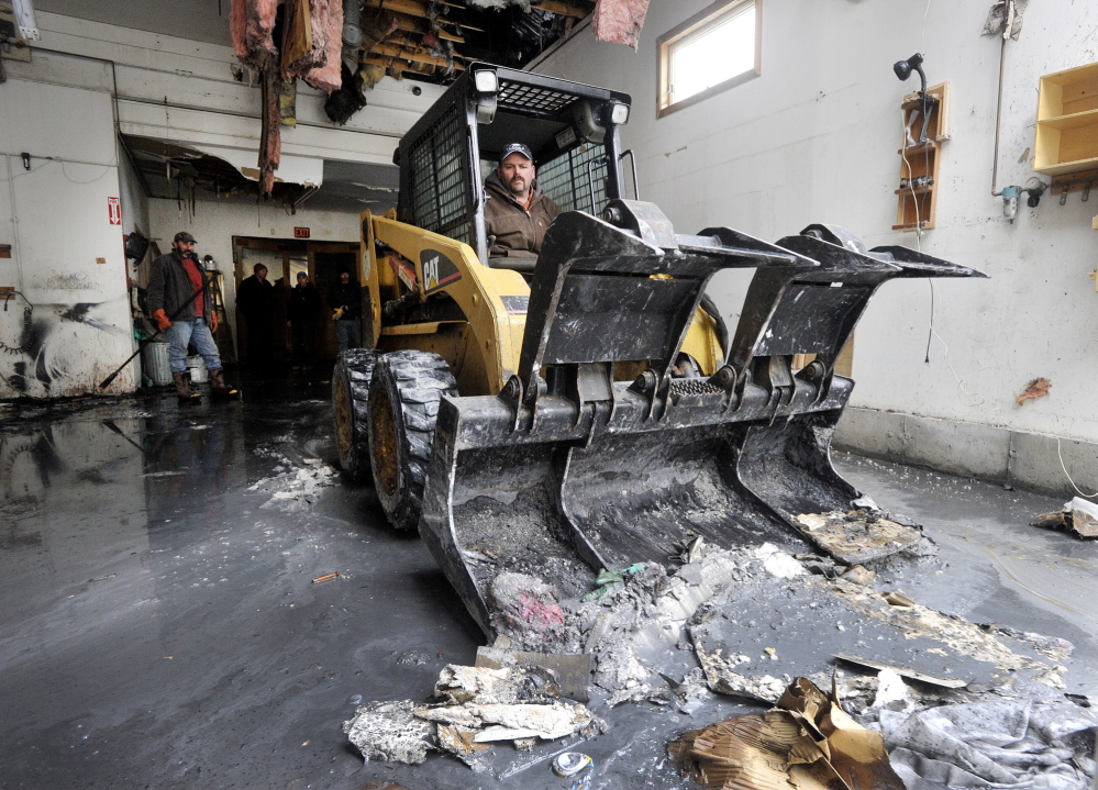 Troy Pride, a friend of business owner David Smith, runs a skid steer Wednesday to clear debris in the partially burned-out building. A structural engineer will survey the damage Thursday and determine whether the 19th-century building can be saved.