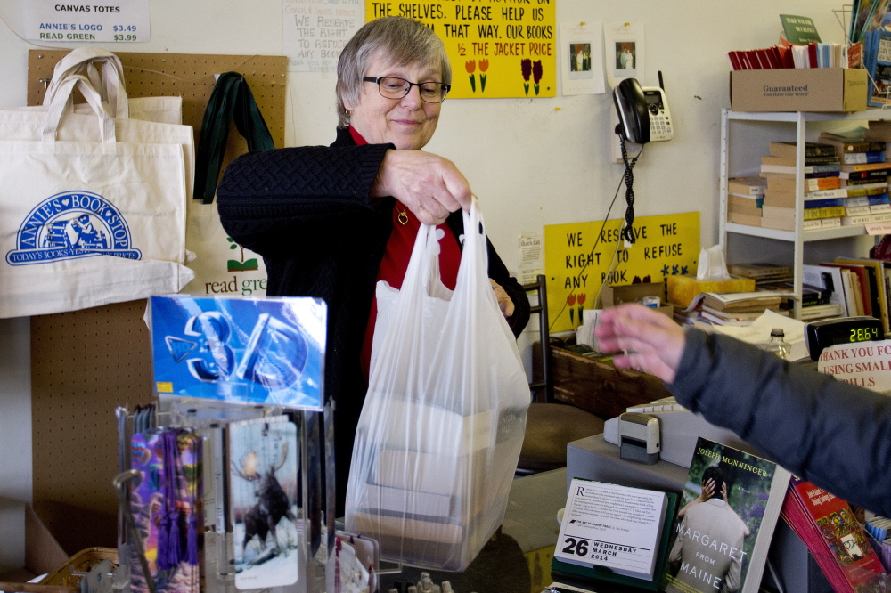 Alice Moisen, owner of the soon-to-be-closed Annie’s Book Stop in Portland, hands a bag of half-price books to a customer on Wednesday.