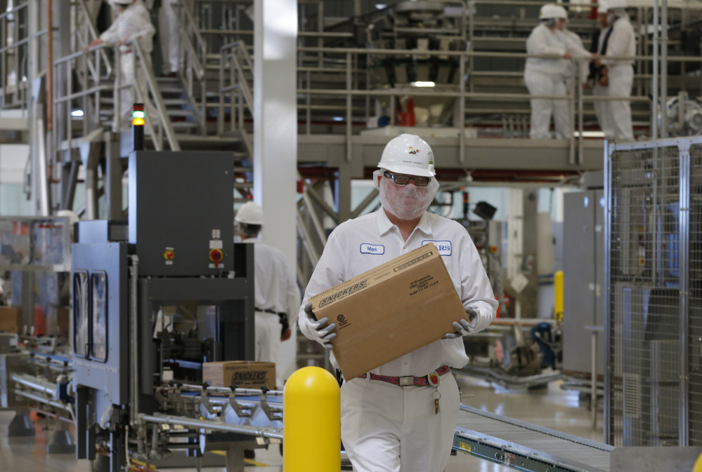 An associate carries a box of Snickers as production begins at the Mars Chocolate North America Topeka Plant on Thursday.
