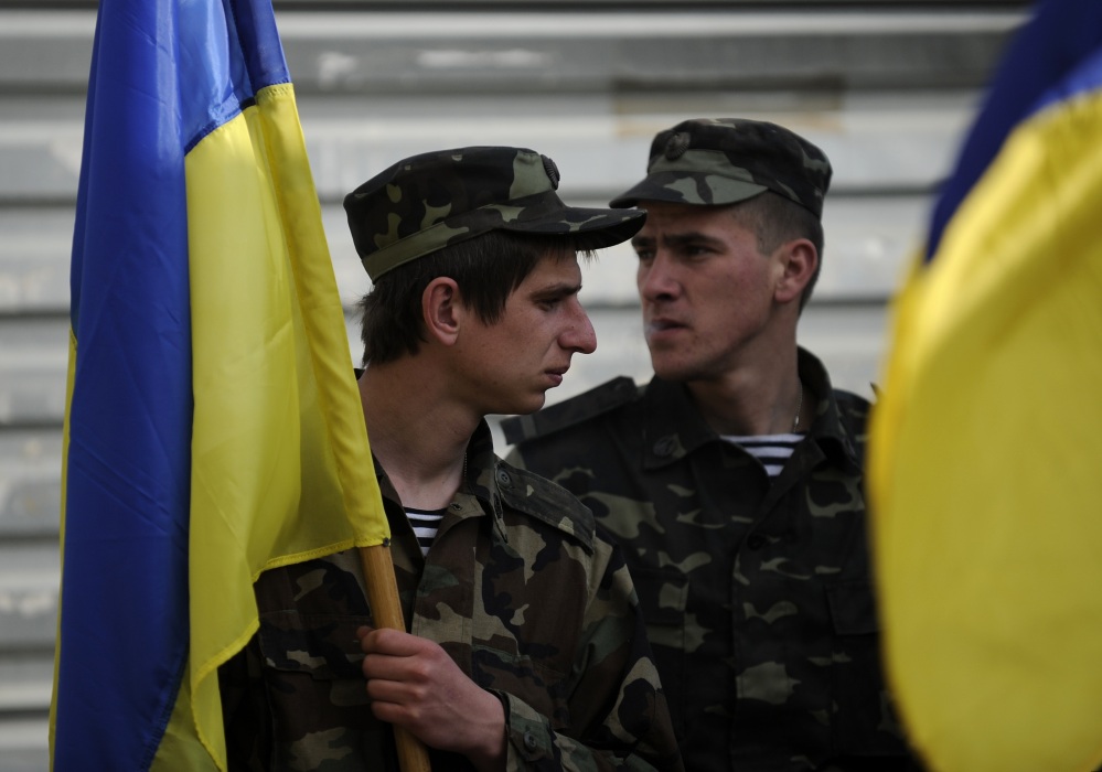 Ukrainian servicemen hold Ukrainian flags as they load their equipment into a truck in readiness to withdraw from the Belbek airbase near Sevastopol, Crimea, on Friday.