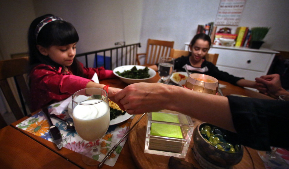 St. Paul, Minn., resident Amy Bryant, right, gives thanks before enjoying a recent evening meal with her daughters Sophie, 5, who is "crazy for milk," and Francesca, 8, who says milk gives her an upset stomach.