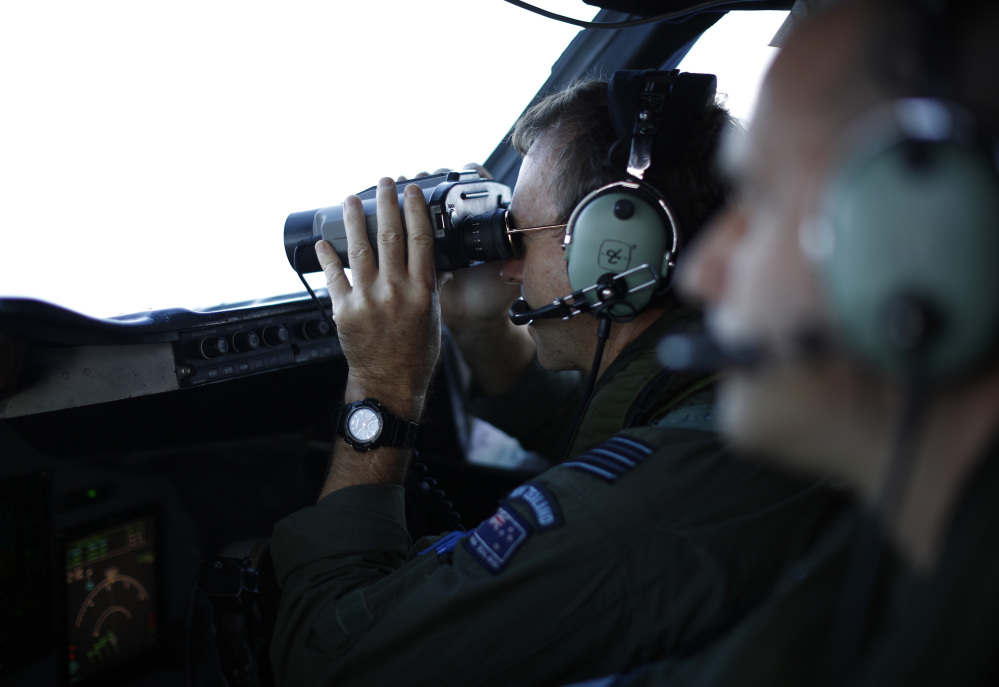 Wing Commander Rob Shearer looks through binoculars on the flight deck of a Royal New Zealand Air Force P-3K2 Orion aircraft searching for missing Malaysian Airlines flight 370 over the southern Indian Ocean, March 29, 2014.