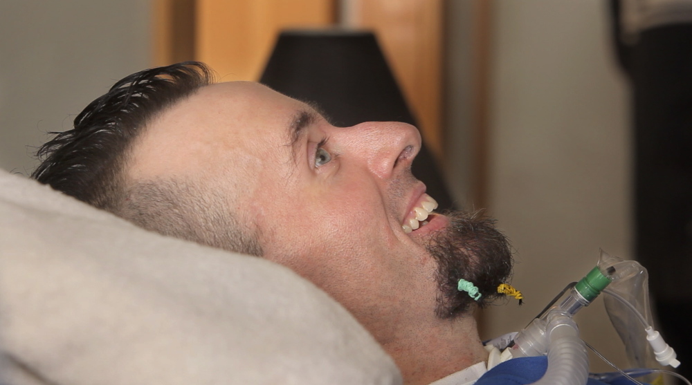 Nick Stanley smiles as he listens to the rapper Spose perform. Stanley is confined to bed because of complications from adult onset spinal muscular atrophy.