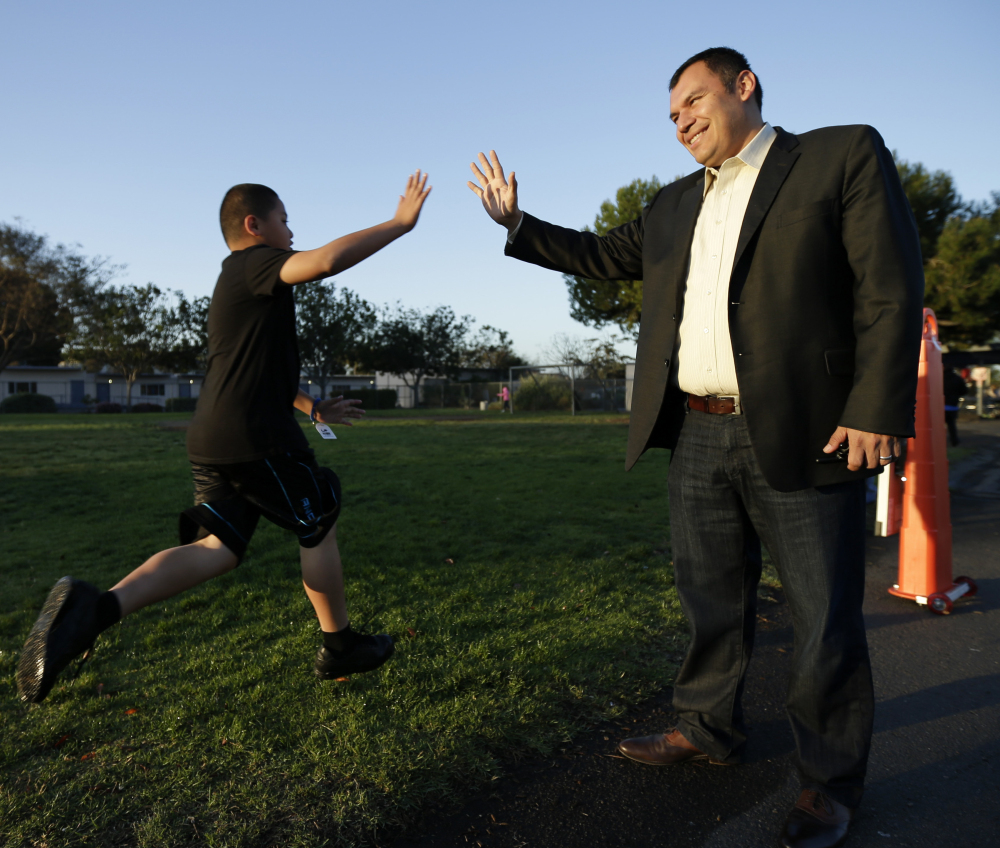 Rice Elementary School Principal Ernesto Villanueva slaps hands with students during an early morning running program in Chula Vista, Calif. Amid alarming national statistics showing an epidemic in childhood obesity, hundreds of thousands of students across the country are being weighed and measured.