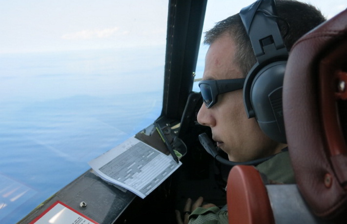 Lt. Chris Kovach peers out the window of a U.S. Navy P3 Orion surveillance aircraft flying over the Indian Ocean west of Indonesia on March 24. The constant scanning messes with your mind, he said.