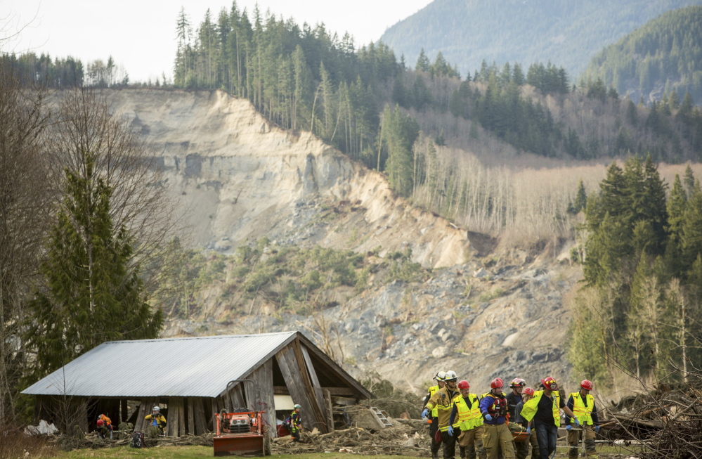 Rescue workers remove a body from the wreckage of homes that were destroyed by a mudslide near Oso, Wash., on March 24. The deadly disaster points to the need for a national inventory of areas that are vulnerable to slides.