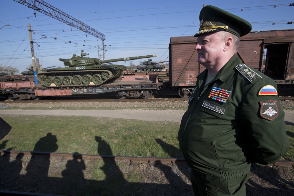 Russian Gen. Igor Lyapin watches Russian tanks, close left, arrive as Ukrainian tanks, center back, are transported to the Ukraine at a railway station in Crimea on Monday.