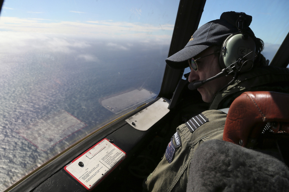 Royal New Zealand Air Force P-3 Orion’s captain, Wing Comdr. Rob Shearer watches out of the window of his aircraft while searching for the missing Malaysia Airlines Flight MH370 in the southern Indian Ocean, Monday, March 31, 2014.