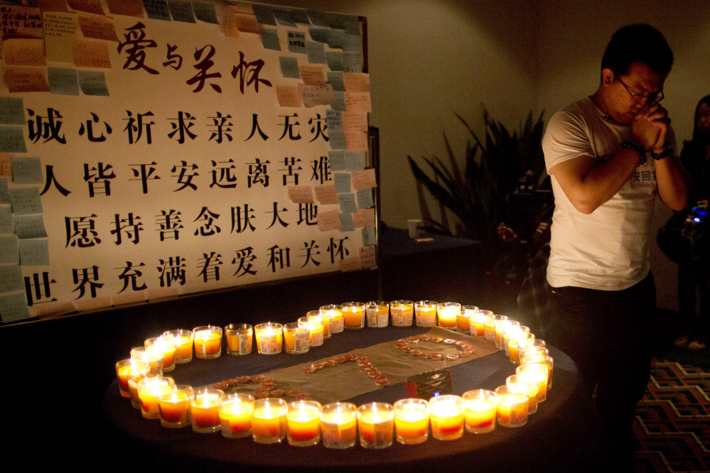 A man, one of the relatives of Chinese passengers onboard Malaysia Airlines Flight 370, prays near candles before a briefing with Malaysian officials at a hotel in Beijing, China, Monday, March 31, 2014.