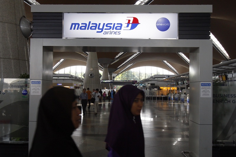 Passengers walk past a signboard of Malaysia Airlines at Kuala Lumpur International Airport in Sepang, Malaysia, on Saturday. International aviation authorities were trying to trace a Malaysia Airlines jetliner carrying 239 people that lost contact with air traffic control on its way from Kuala Lumpur to Beijing.