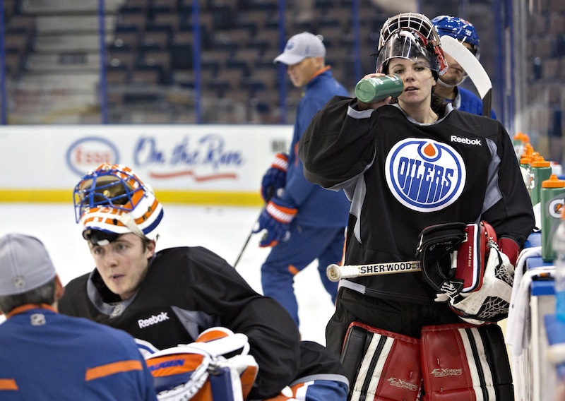 Canadian Olympic women's team goalie Shannon Szabados takes a water break during practice with the Edmonton Oilers NHL hockey team Wednesday. Oilers goaltender Ben Scrivens is at left facing the camera.