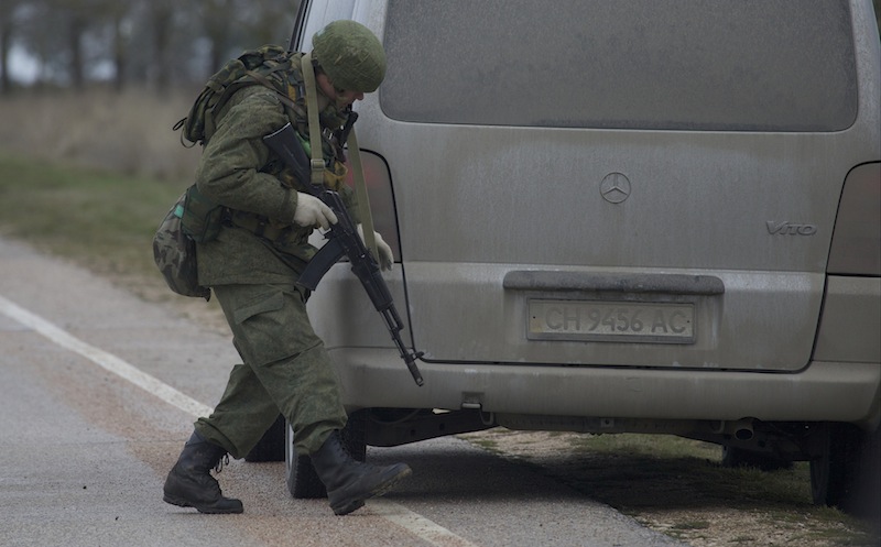 An unidentified gunman searches a vehicle while he and others block the road toward the military airport at the Black Sea port of Sevastopol in Crimea, Ukraine, Friday, Feb. 28, 2014. Russian troops took control of the two main airports in the strategic peninsula of Crimea, Ukraine's interior minister charged Friday, as the country asked the U.N. Security Council to intervene in the escalating conflict. Russian state media said Russian forces in Crimea denied involvement. No violence was reported at the civilian airport in Crimea's capital of Simferopol or at the military airport in the Black Sea port of Sevastopol, also part of Crimea.