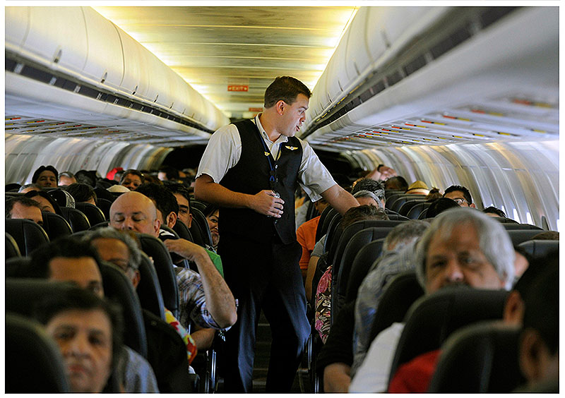 Allegiant Air flight attendant Chris Killian settles his passengers in coach class before their aircraft pushes back from the terminal at McCarran International Airport in Las Vegas.