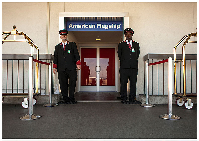 American Airlines skycaps Alex Abel Gonzalez, left, and Frederick Pearson wait outside the AA Flagship lounge at Los Angeles International Airport