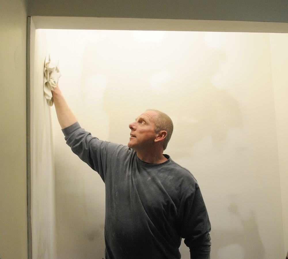 for pets and Amy: After sanding the wall, Steve Gagne, owner of S n S Multitasking, wipes off dust before painting a wall in the room he is renovating for the Amy Buxton Pet Pantry at South Parish Congregational Church in Augusta.