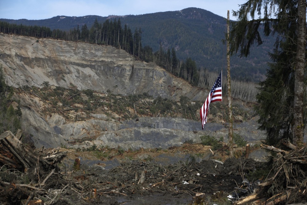 An American flag flies as half-staff Monday from the only cedar post left standing at the scene of a deadly mudslide that destroyed Oso, Wash., leaving at least 24 dead. The debris field is 70 feet deep in places.