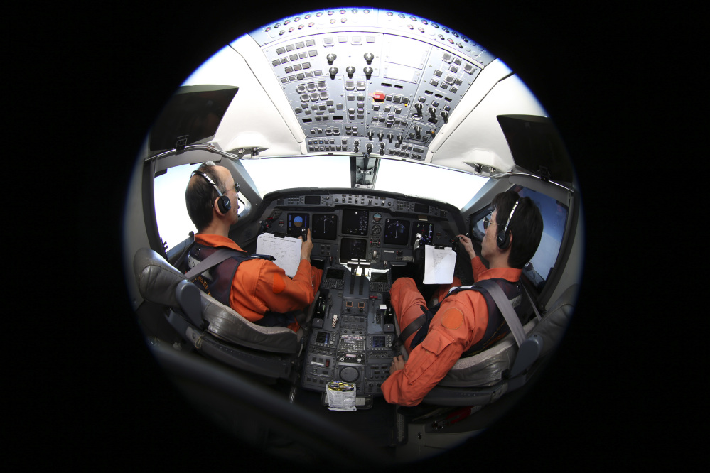 Captain of the Japan Coast Guard Gulfstream Makoto Hoshi left, and his co-pilot Shunichi Yumiza sit in the cockpit during a search for the missing Malaysia Airlines Flight MH370 in Southern Indian Ocean, near Australia, Tuesday.