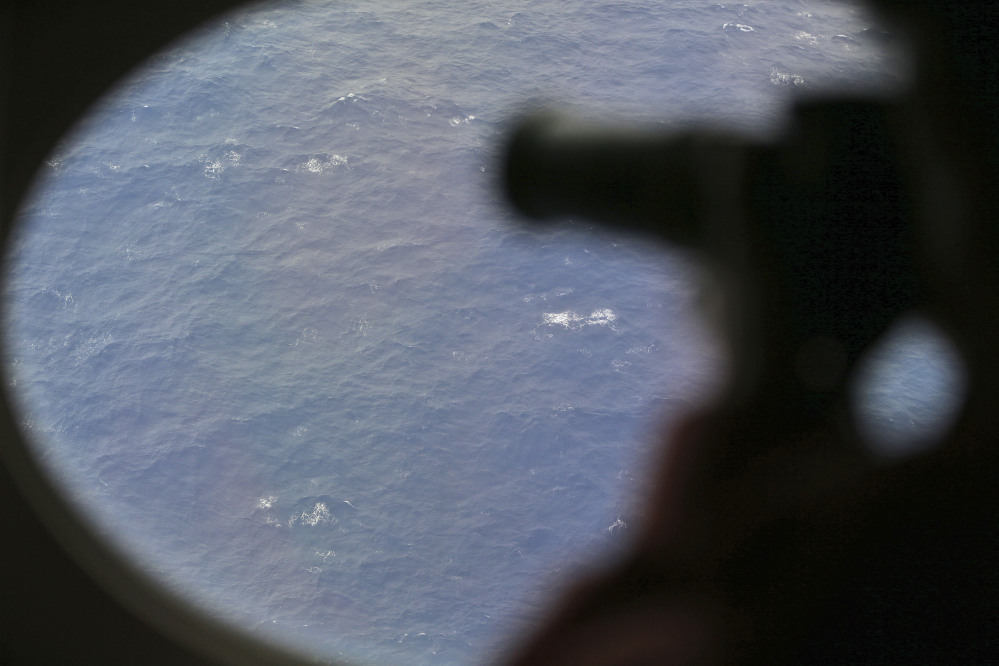 An observer on a Japan Coast Guard Gulfstream aircraft takes photos out of a window while searching for the missing Malaysia Airlines Flight MH370 in Southern Indian Ocean, near Australia, Tuesday, April 1, 2014. Bad weather and poor visibility caused the search to be called off early with the coast guard plane only completing one of its three 210 nautical mile legs.