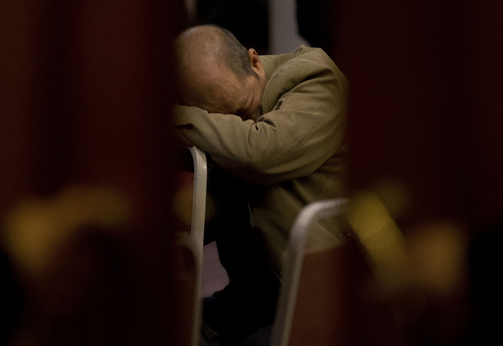 In this March 18, 2014 file photo, a relative of Chinese passengers aboard the missing Malaysia Airlines Flight MH370 rests on a chair as he waits for a news briefing by the Airlines’ officials at a hotel ballroom in Beijing, China. Malaysia’s credibility in the hunt for FLight 370 is being challenged again, especially by relatives of Chinese passengers.