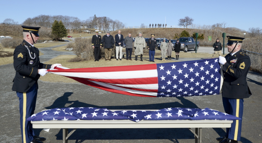 Sgt. David Chabe and Sgt. 1st Class Norman Voter fold one of eight flags to be presented to descendants, standing at back, of George Osborn Sr. who served with his seven sons in the Revolutionary War.