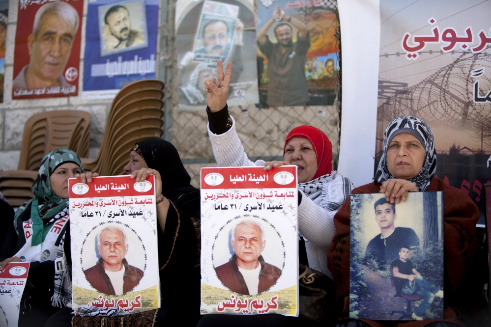 Women hold portraits of Palestinian prisoners held in Israeli jails during a rally calling for their release in the West Bank city of Ramallah on Tuesday. Arabic on the posters reads, “Dean of prisoners, Karim Younis, 21 years in prison.”