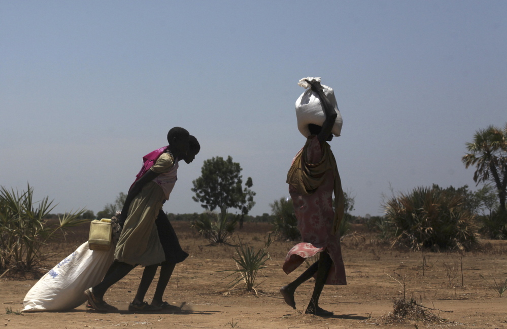 Women carry food distributed in Nyal in South Sudan on Tuesday. Air drops of food are three times more expensive than road deliveries but crucial in the inaccessible area.