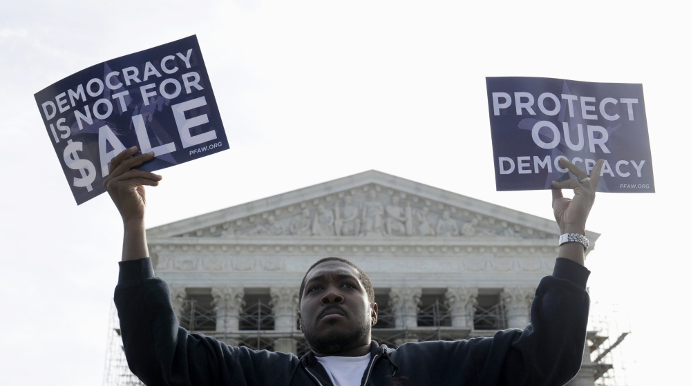 Cornell Woolridge of Windsor Mill, Md., takes part in a demonstration outside the Supreme Court in Washington last fall when the court heard arguments on campaign finance. The Supreme Court struck down limits Wednesday on the overall campaign contributions individual donors may make to candidates, political parties and political action committees.