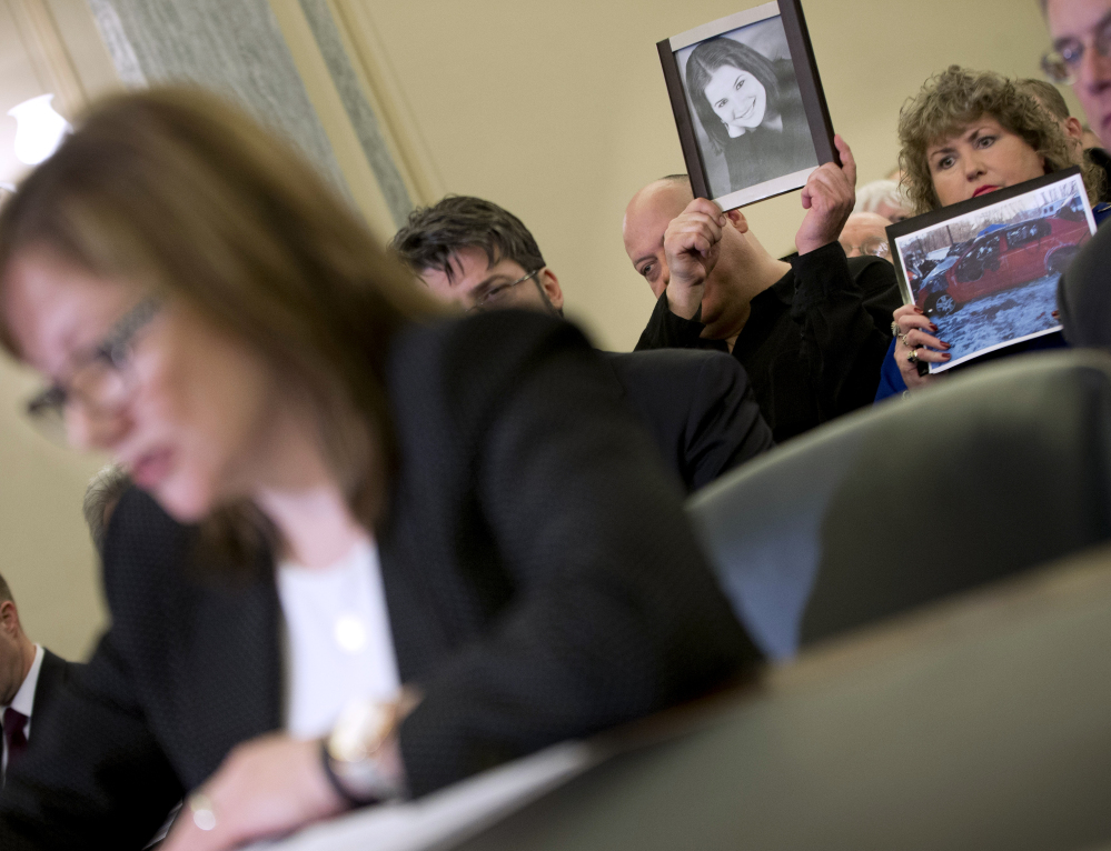 Leo Ruddy, center, and his wife Mary Theresa Ruddy, right, of Scranton, Pa., hold up photographs of their daughter Kelly Erin Ruddy and the 2005 Chevy Cobalt that she crashed and died in, as they sit in the audience to listen to testimony by General Motors CEO Mary Barra, left, on Capitol Hill in Washington on Wednesday before the Senate Commerce, Science and Transportation subcommittee.