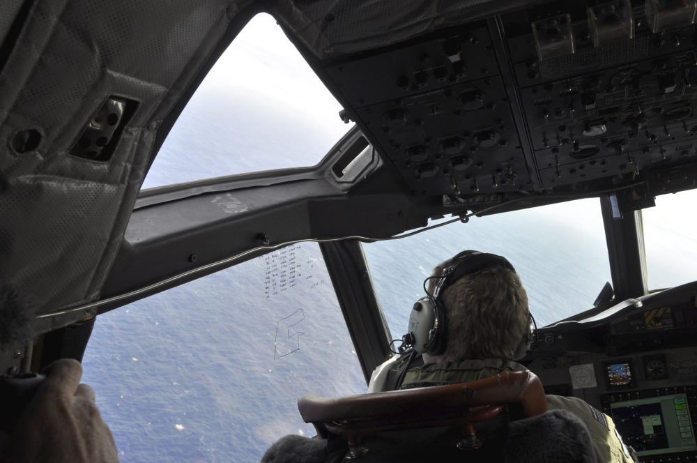 In this photo made available Thursday, April 3, 2014, a crewman on a Royal New Zealand Air Force P-3 Orion Rescue Flight 795 searches for debris from the missing Malaysia Airlines Flight MH370, in southern Indian Ocean, 1,500 kilometers northwest of Perth, Australia.