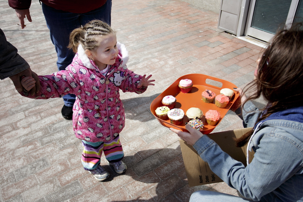 Shawna Torres, 3, of Portland ponders a difficult decision as she surveys the free cupcakes offered by Lindsy Bryce during an informal remembrance for Randee Bucknell on Congress Street Thursday.