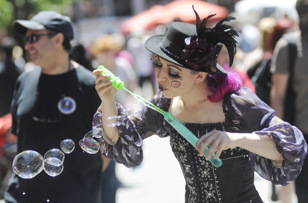 Miss Polly, a member of the goth-inspired street performance group Dark Follies, blows bubbles on Exchange Street in Portland during the Old Port Festival in June 2012.