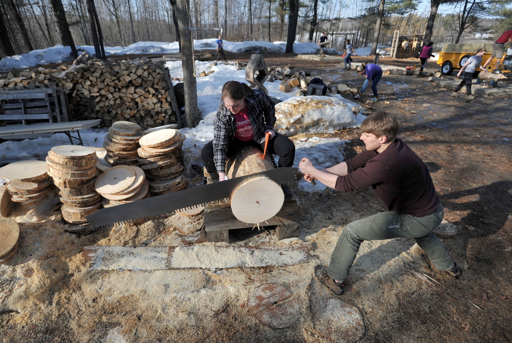 Chris Krasniak, 20, works the buck saw as Tara Chizinski, 21, oils the saw and wedges the disc during timber sports practice at Colby College on Thursday.