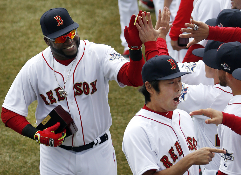 Boston Red Sox designated hitter David Ortiz, left, and relief pitcher Koji Uehara, lower right, celebrate with teammates after receiving their 2013 World Series rings at Fenway Park in Boston on Friday during home opening day ceremonies prior to a baseball game between the Boston Red Sox and the Milwaukee Brewers.